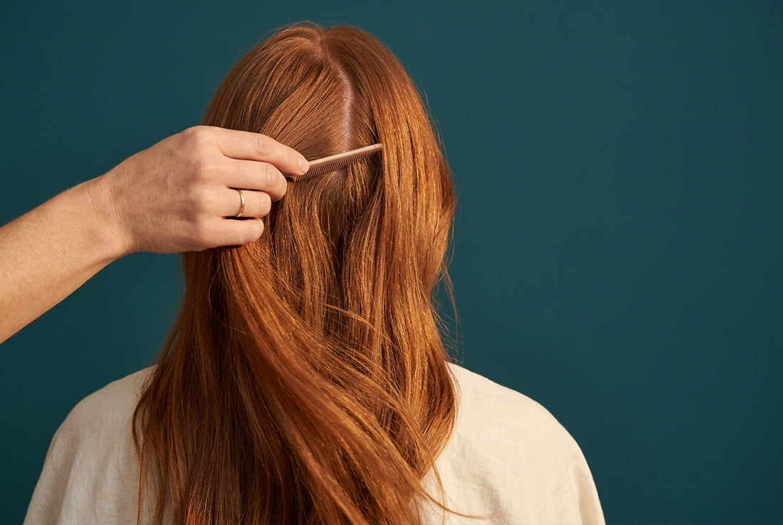 Coiffeuse dégageant les racines saines d'une chevelure rousse avec extensions